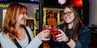 Two women cheers glasses at Mother Muffs, one of our picks for Galentine's Day karaoke