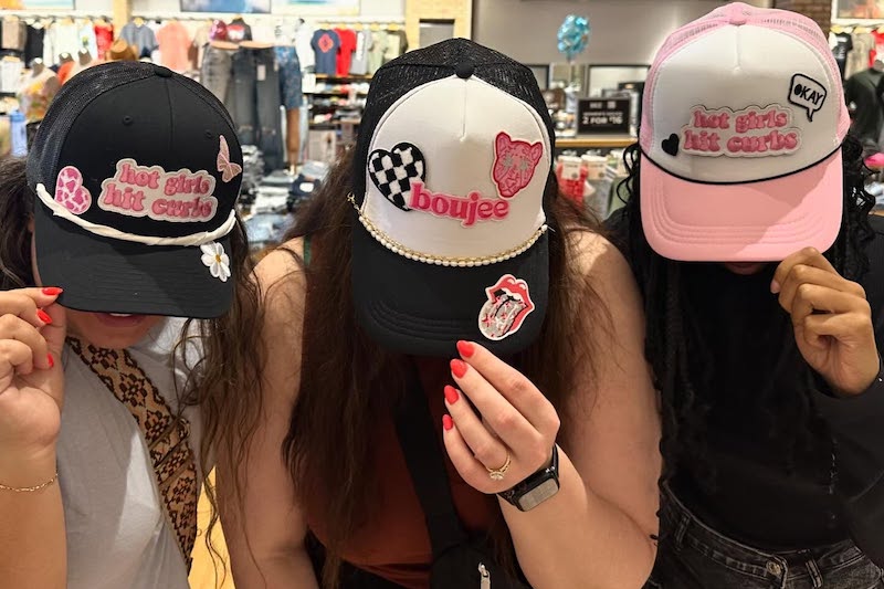 Three women show off their hats while shopping at Eclectic + Co., where there's a Galentine's Day Party this year.
