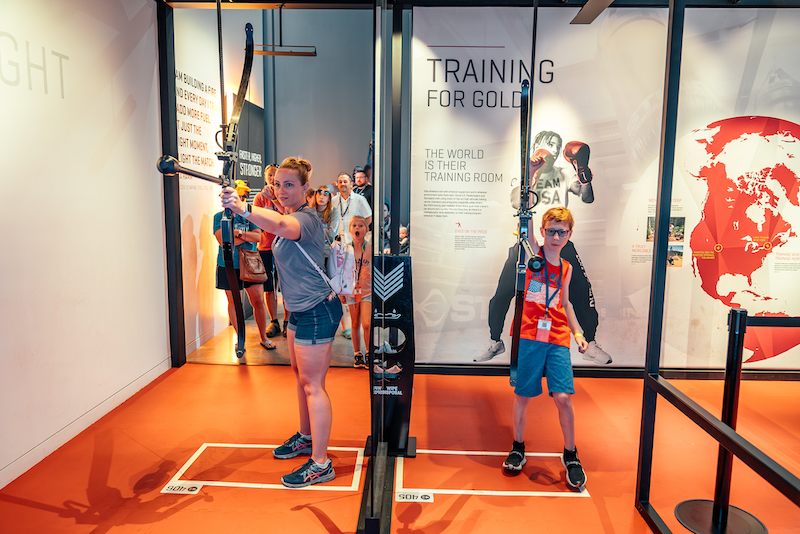 A mother and son try the interactive archery exhibit at the U.S. Olympic Museum in Colorado Springs.