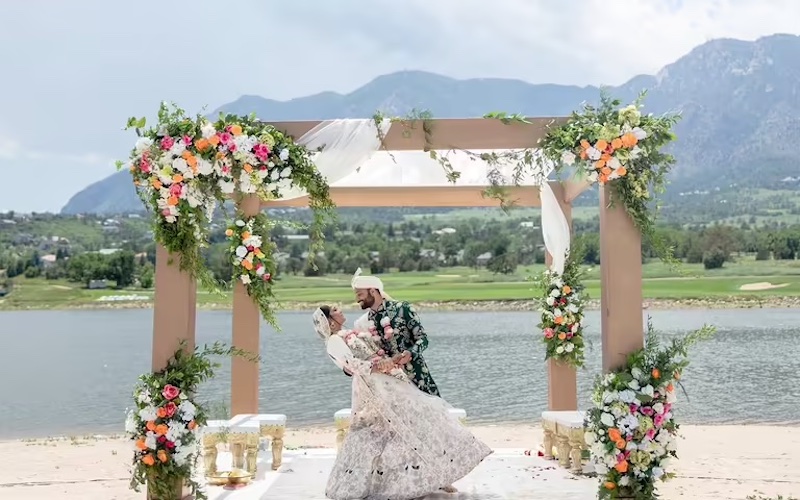 A cultural wedding at Cheyenne Mountain Resort with a beautiful floral pergola in front of the lake and Cheyenne Mountain.