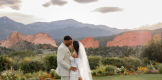 A bride and groom embrace on the lawn at Garden of the Gods Resort and Club with Pikes Peak and Garden of the Gods in the background. Photo courtesy of Garden for he Gods Resort and Club.