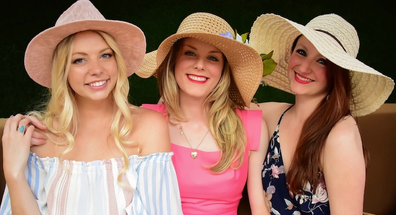 Three women in sundresses and stylish hats, dressed to impress for Kentucky Derby parties in Colorado Springs.