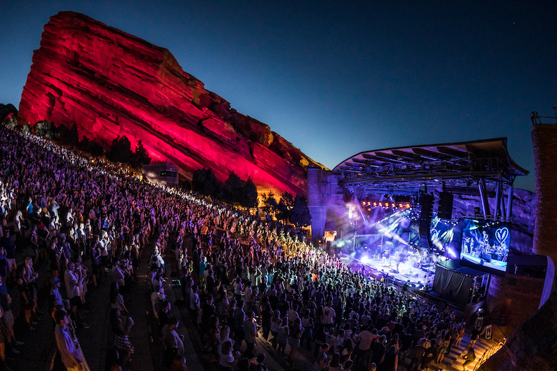 A nighttime concert at Red Rocks with the stage and rocks lit up. The iconic venues hosts some of the best concerts in Colorado every year,