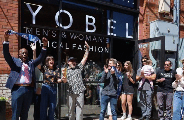 Large group of people stand in front of storefront for ribbon cutting ceremony at Yobel in downtown Colorado Springs.