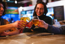 Friends cheers with beer glasses at Voodoo Brewing, enjoying cheap drinks with the Crafts and Drafts Passport in Colorado Springs.