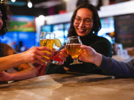 Crafts & Drafts Passport Levels Up 10 Years of Drink Deals Friends cheers with beer glasses at Voodoo Brewing, enjoying cheap drinks with the Crafts and Drafts Passport in Colorado Springs.