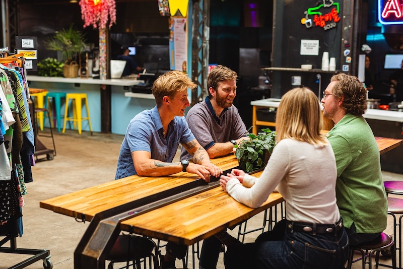 People sit together around a table at COATI in the New South End, a popular neighborhood in Colorado Springs