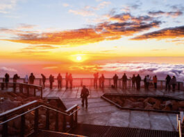 This Year You Can Watch Sunrise and Sunset on Pikes Peak A group of people stands on the observation deck and watches sunrise on Pikes Peak.