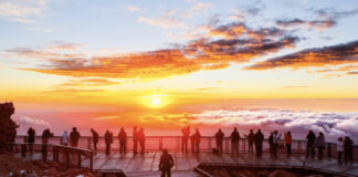 This Year You Can Watch Sunrise and Sunset on Pikes Peak A group of people stands on the observation deck and watches sunrise on Pikes Peak.