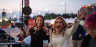 Two women wave with excitement at Taste of Pikes Peak, the Colorado Springs food festival of the year