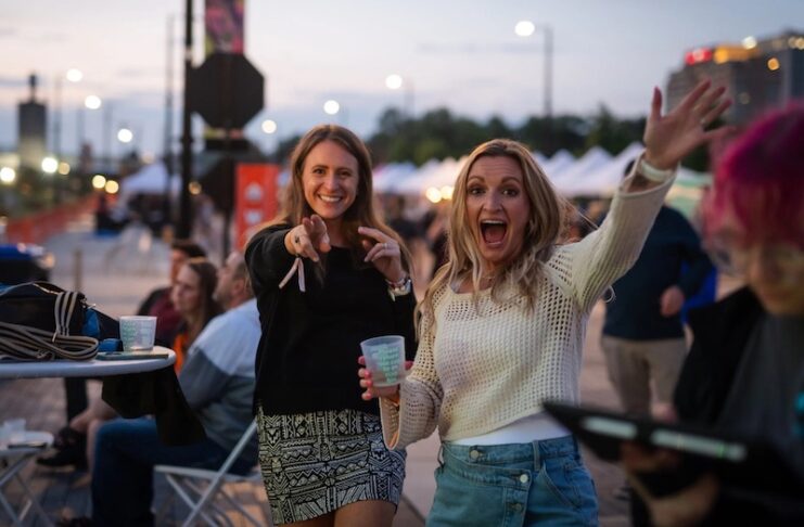Two women wave with excitement at Taste of Pikes Peak, the Colorado Springs food festival of the year