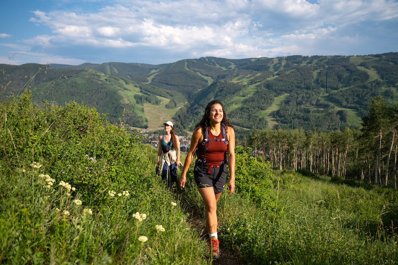 Two women hike among wildflowers on a trail above Vail. 