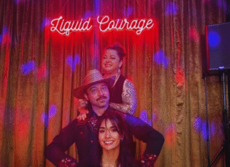 Liquid Courage Three people stand in front of stage with neon sign saying Liquid Courage.