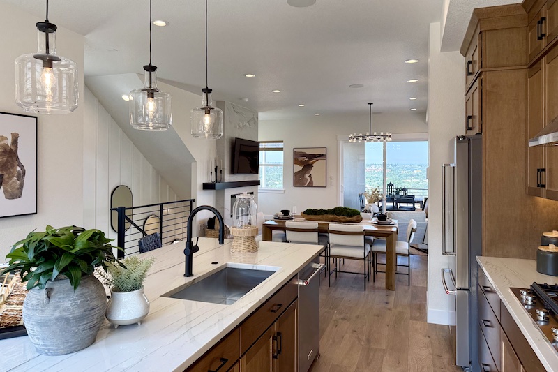 View of the open floor plan kitchen, dining room and living room inside the Ridgeway model home by Toll Brothers at Gold Hill in Colorado Springs.