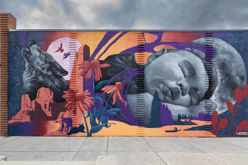 Mural of sleeping baby and howling wolf. Harrison by AikoSzymczak, part of Art on the Streets in Downtown Colorado Springs and great art to explore during Arts Month in Colorado Springs.