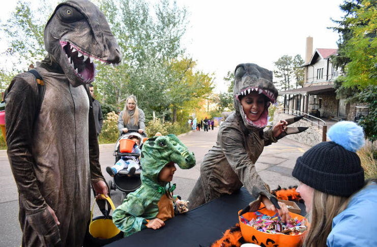 A family in dinosaur costumes trick or treats at Cheyenne Mountain Zoo's Boo at the Zoo for Halloween in Colorado Springs.