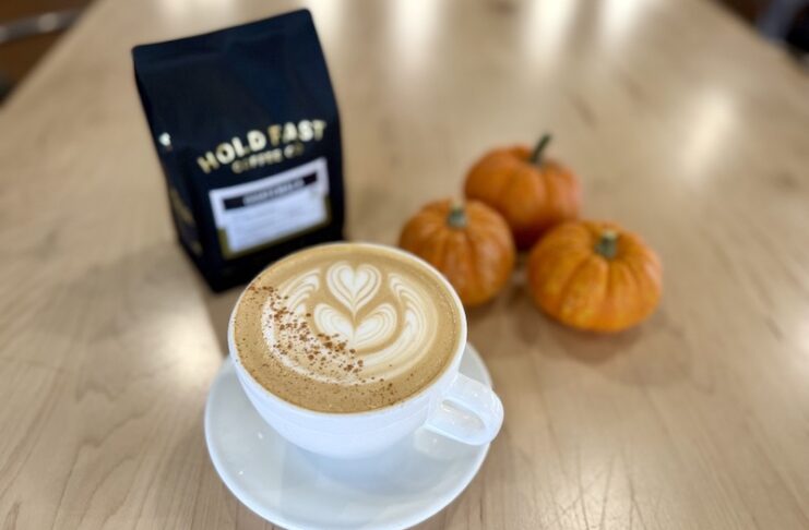 Mini pumpkins, a bag of coffee beans and a pumpkin pie latte at Hold Fast Coffee Company, one of the best Colorado Springs coffee shops for fall seasonal drinks.