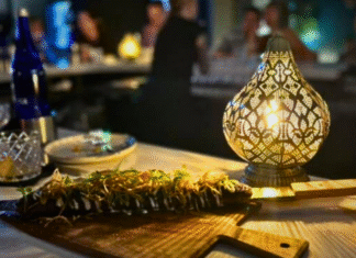 Latin Social Plated kebab presented on carving board with warm light and diners in background.
