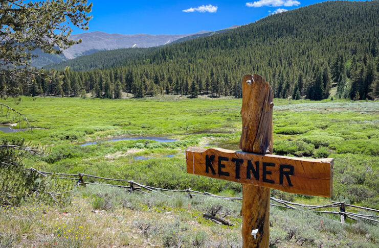 A cross labeled Ketner is a grave marker in this scenic valley and mountain view in the Tincup Cemetery in Tincup, Colorado.