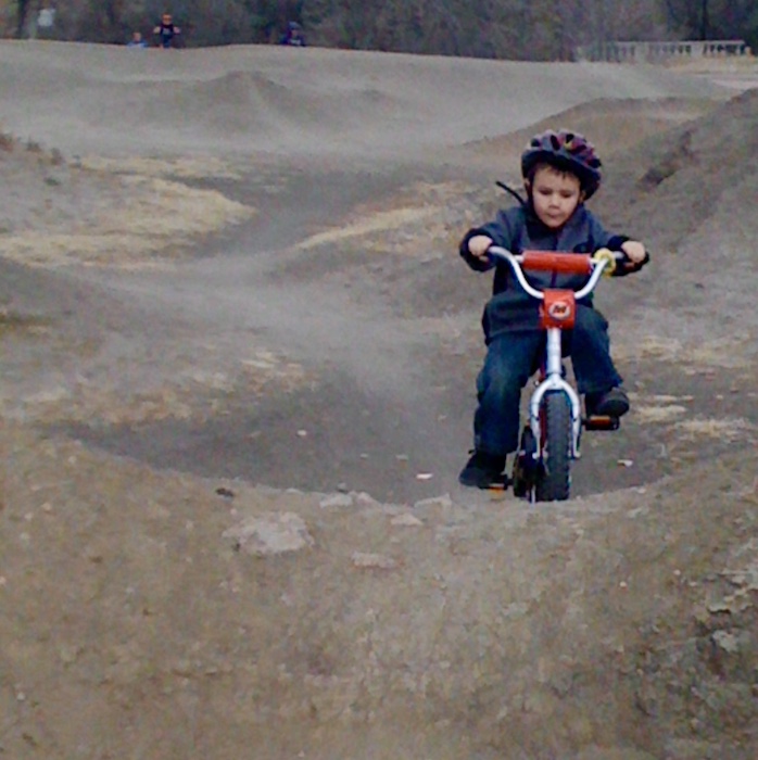 A preschool boy rides a bike on the dirt trails at Goose Gossage Bike Park. Mountain biking is one of the great things to do in winter with kids in Colorado Springs.