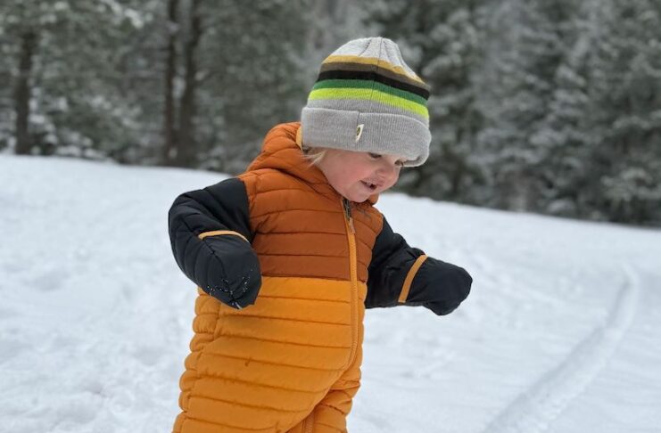 A toddler in a down snow suit plays in the snow. Hiking trails offer fun winter things to do in Colorado Springs.