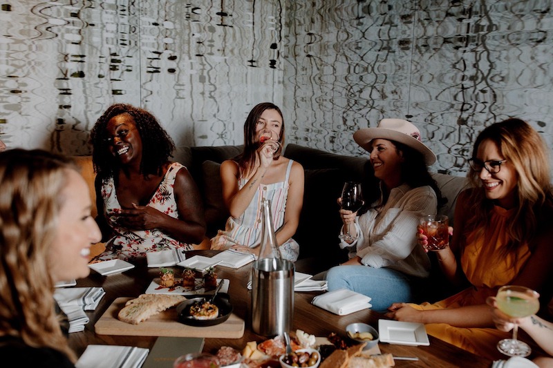 A group of women enjoy wines and charcuterie boards for Galentine's Day at Vine and Wheel wine bar in Colorado Springs.