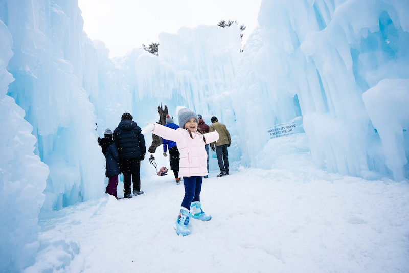 A little girl celebrates in the ice fortress of Ice Castles. 