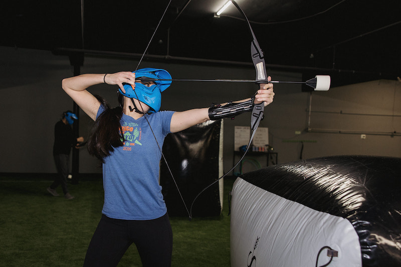 An archer shoots an arrow from behind an airbag in a game of archery dodgeball.