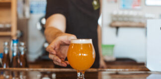 Goat Patch bartender serving a craft beer in Colorado Springs.