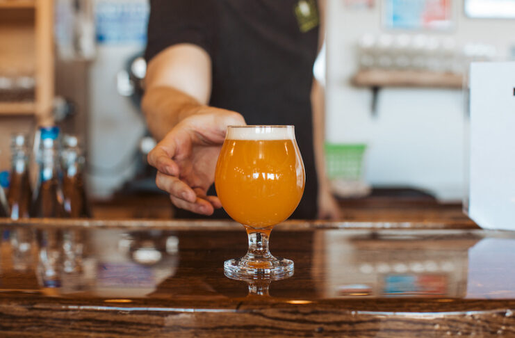 Goat Patch bartender serving a craft beer in Colorado Springs.