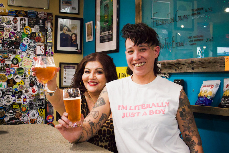 Jess Fierro and an employee raise a glass at the bar in Atrevida Beer Colorado.