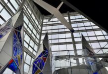 Inside the glass atrium at the U.S. Air Force Academy Visitor Center with stained glass tetrahedrons and a glider suspended overhead.