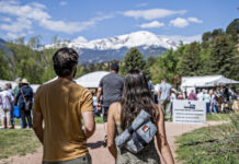 A couple walks toward the tents at the Garden of the Gods Art Festival with Pikes Peak in the background.