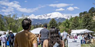 A couple walks toward the tents at the Garden of the Gods Art Festival with Pikes Peak in the background.