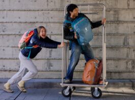 Here Are Our Best Backpacks for Traveling A girl pushes a guy on a luggage cart while wearing Cotopaxi Allpa Travel Packs