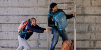 A girl pushes a guy on a luggage cart while wearing Cotopaxi Allpa Travel Packs