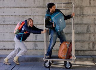 A girl pushes a guy on a luggage cart while wearing Cotopaxi Allpa Travel Packs