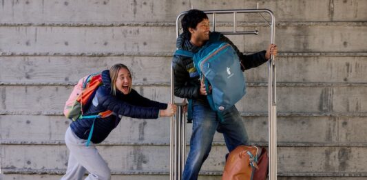 Here Are Our Best Backpacks for Traveling A girl pushes a guy on a luggage cart while wearing Cotopaxi Allpa Travel Packs