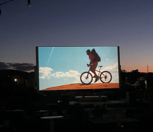 CO150 Film Fest Screens Film Festivities Across Colorado An outdoor movie screen shows a film at sunset for the CO150 Film Festival