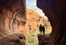 Two hikers silhouetted in the sun at Subway Cave in Sedona, Arizona.