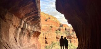 Two hikers silhouetted in the sun at Subway Cave in Sedona, Arizona.