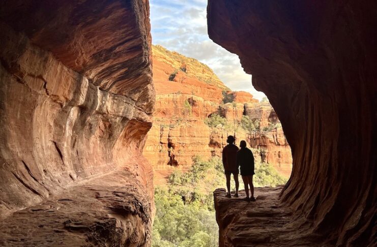 Two hikers silhouetted in the sun at Subway Cave in Sedona, Arizona.