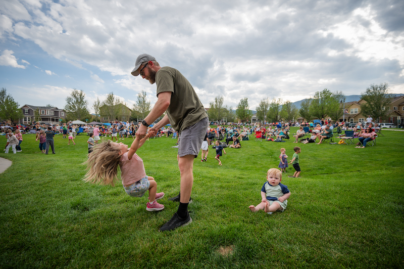 A dad twirls his daughter on the lawn at Music on the Mesa at Gold Hill Mesa.