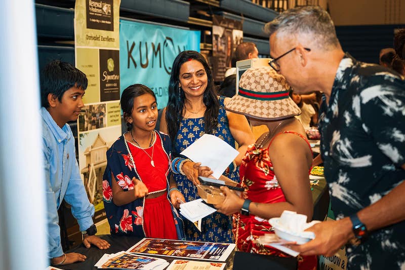 A girl and her mother share information at a booth at the Indian Food Festival in Colorado Springs