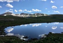 The Best Mountain Passes in Southern Colorado Peaks and clouds reflected in a lake at the summit of Independence Pass, one of the most scenic drives in Colorado.