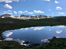 The Best Mountain Passes in Southern Colorado Peaks and clouds reflected in a lake at the summit of Independence Pass, one of the most scenic drives in Colorado.