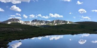 The Best Mountain Passes in Southern Colorado Peaks and clouds reflected in a lake at the summit of Independence Pass, one of the most scenic drives in Colorado.