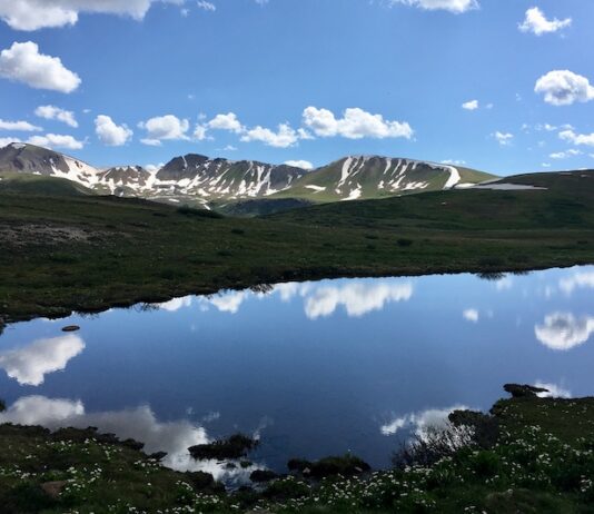 The Best Mountain Passes in Southern Colorado Peaks and clouds reflected in a lake at the summit of Independence Pass, one of the most scenic drives in Colorado.