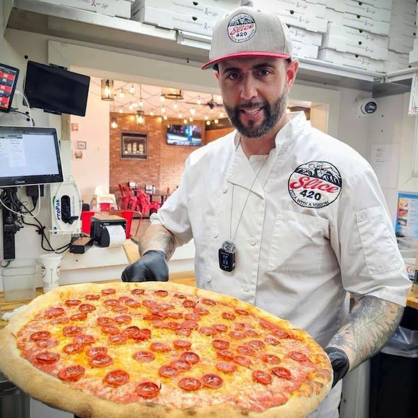 Slice 420 owner Christian Patriarca serves a giant pizza.