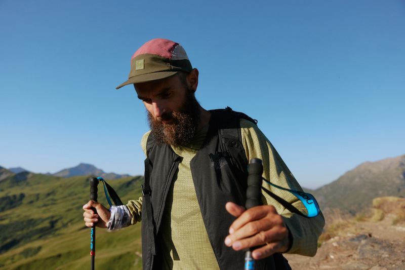 A man hikes wearing a Buff Domus 5 Panel Cap, one of our favorite hiking gear picks.